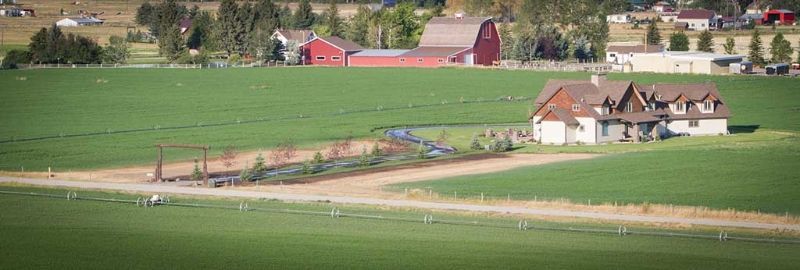 An aerial view of a farm with a red barn in the background.