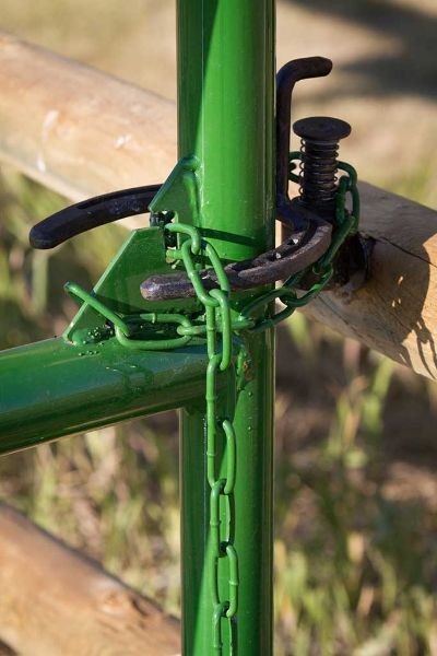 A green fence post with a chain attached to it.
