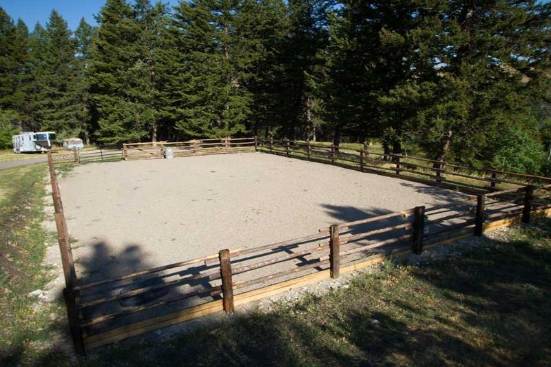 A wooden fence surrounds a sandy area in the middle of a forest.