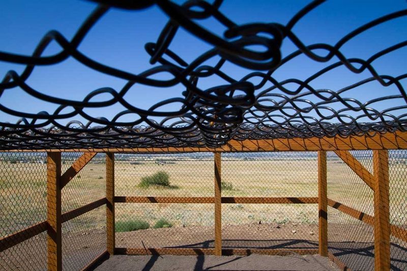 A wooden structure with a chain link fence surrounding it.