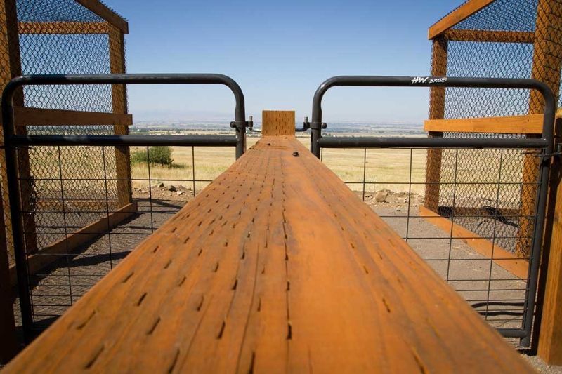 A wooden fence with a view of a field behind it.