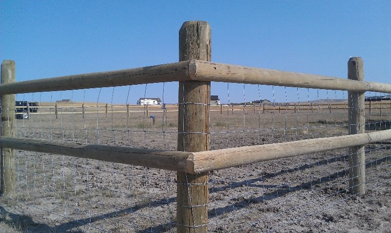 A wooden fence is in the middle of a dirt field.