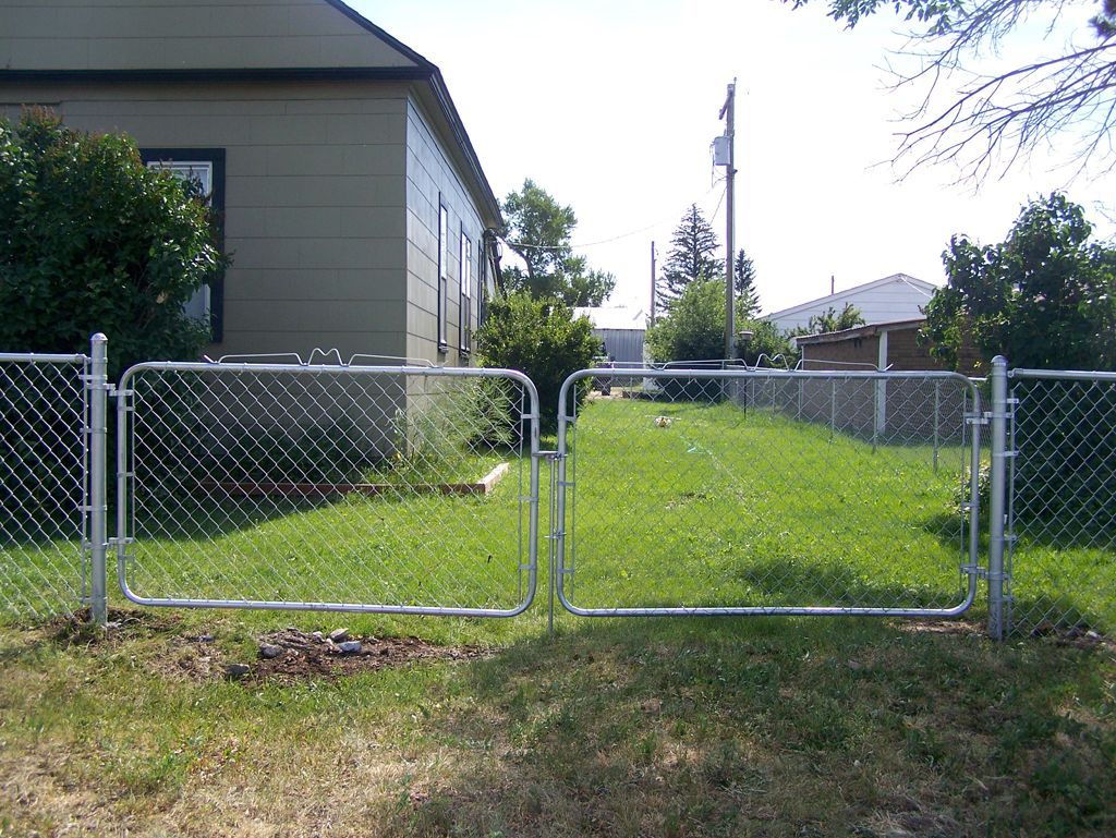 A chain link fence with a gate in front of a house.