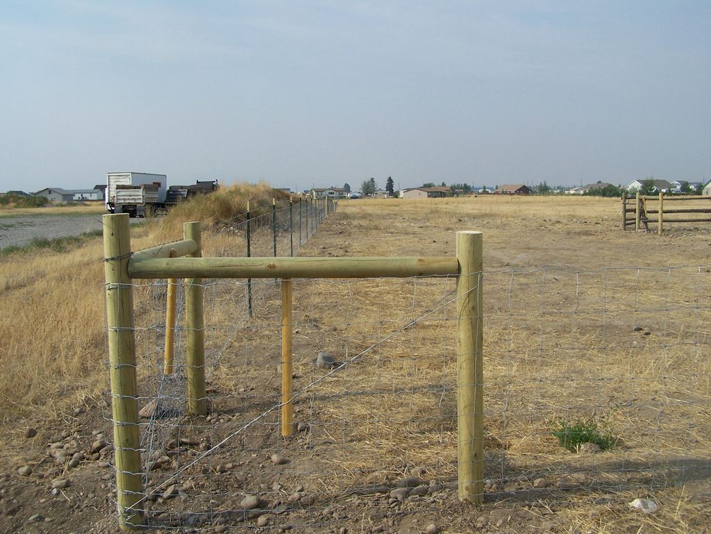 A wooden fence is in the middle of a field.