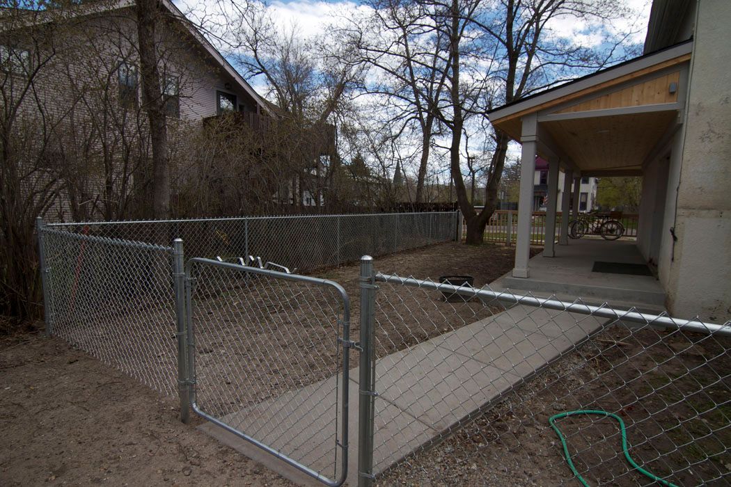 A chain link fence is surrounding a concrete walkway in front of a house.