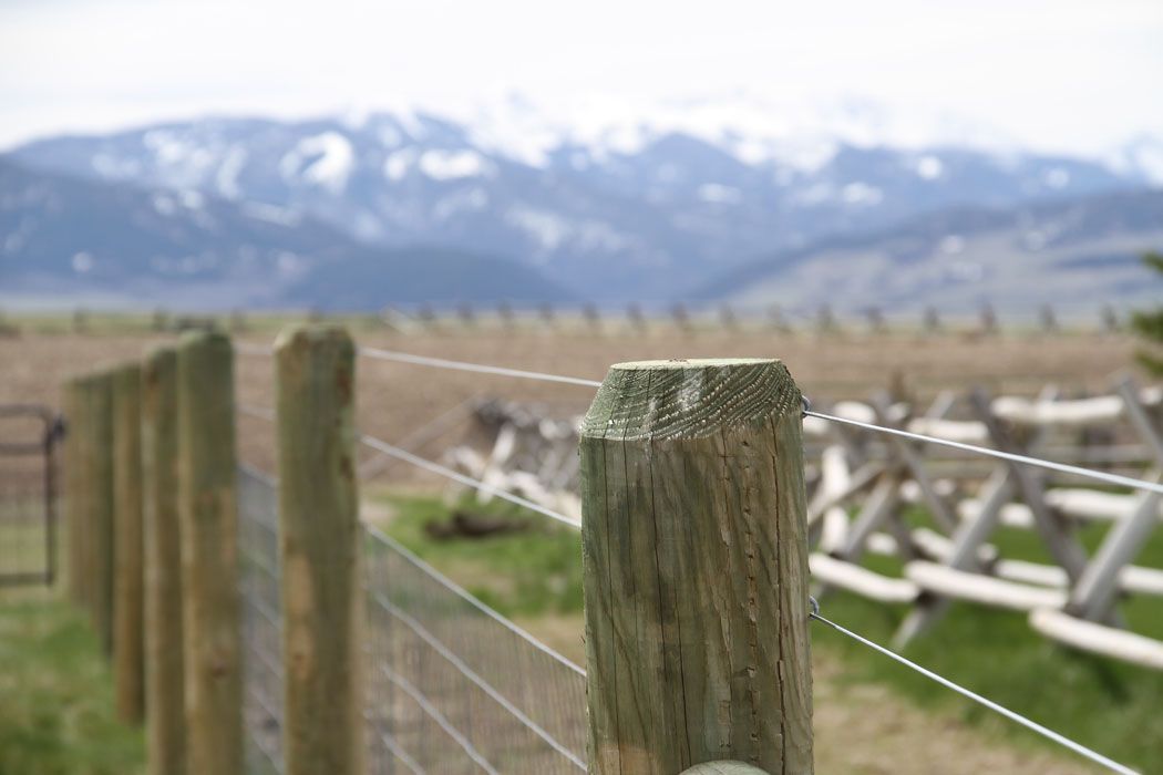 A fence with mountains in the background and a wooden post in the foreground.