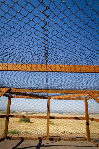 A chain link fence with a blue sky in the background.
