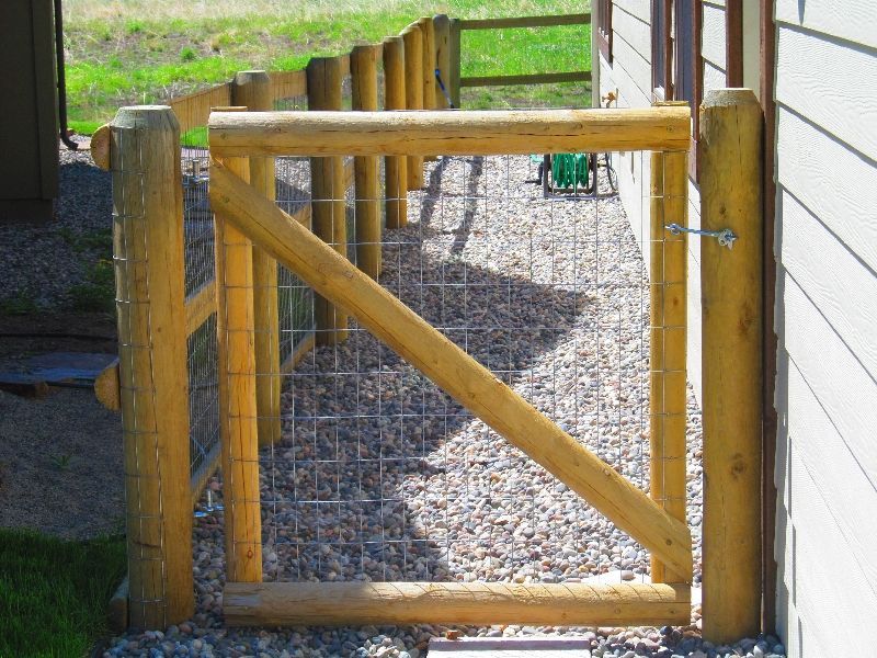A wooden gate with a chain link fence behind it.