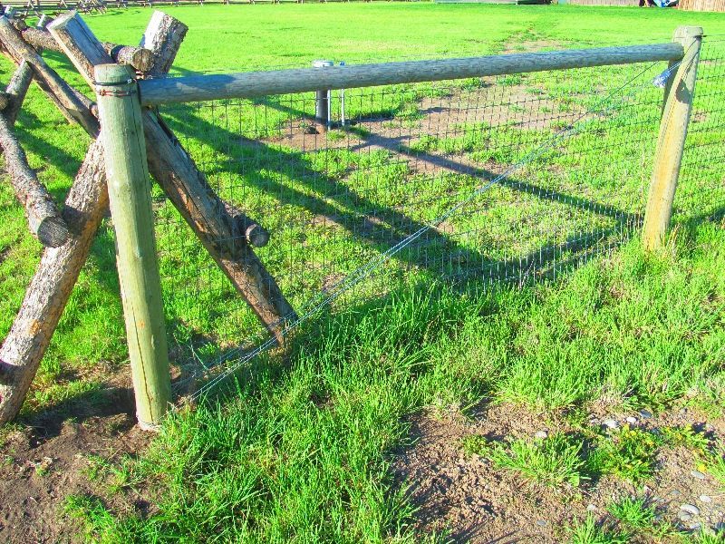 A wooden fence is sitting in the middle of a grassy field.