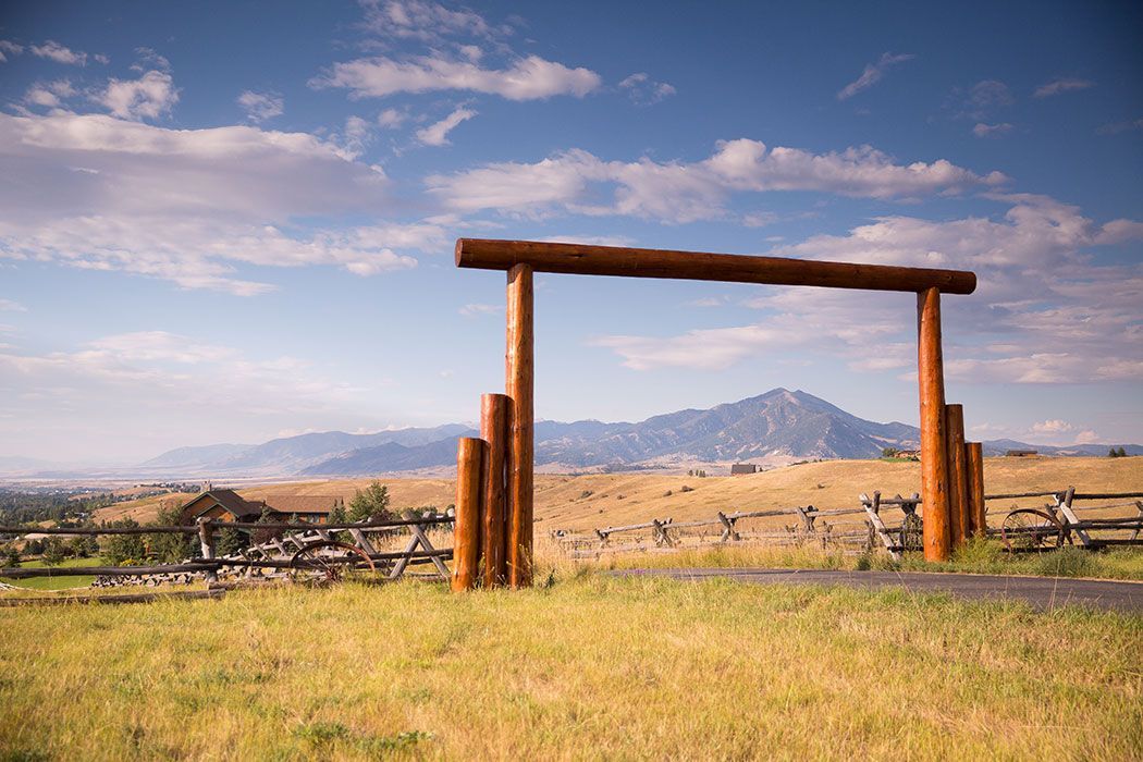 A wooden gate in the middle of a field with mountains in the background.