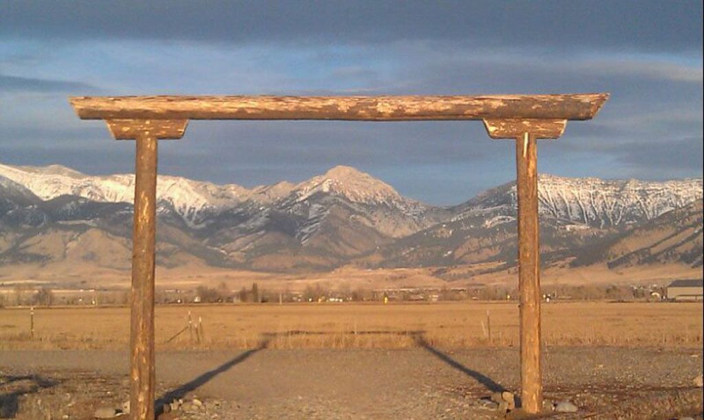A wooden archway with mountains in the background.
