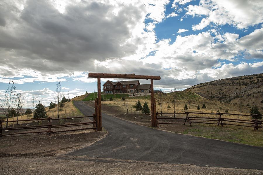 A road with a fence and a house in the background.