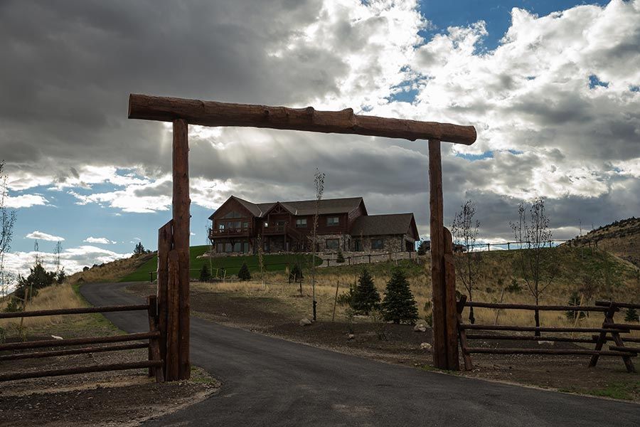 A large house is behind a wooden gate on a cloudy day.