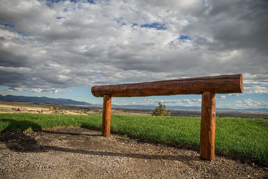 A wooden fence surrounds a grassy field with mountains in the background.