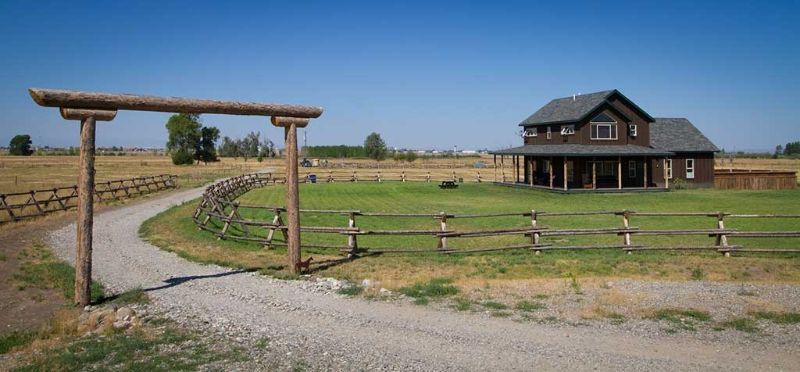 A house is surrounded by a wooden fence and a gravel road.