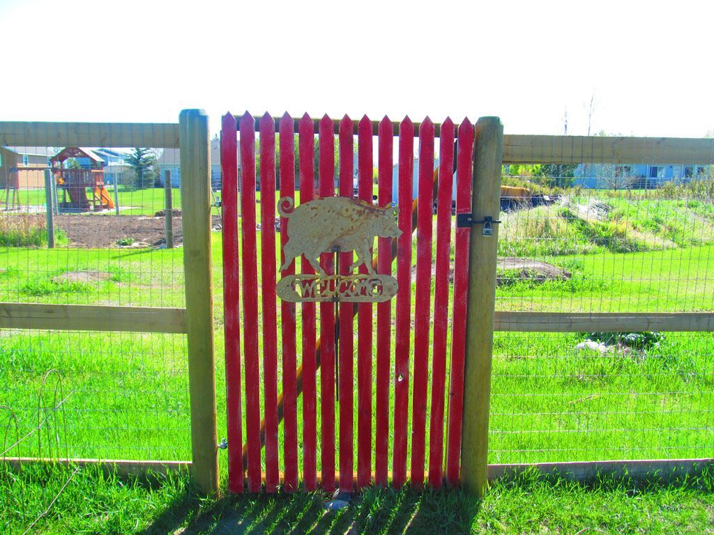 A red wooden gate with a bear on it.