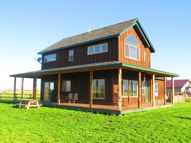 A house with a porch and a picnic table in front of it.
