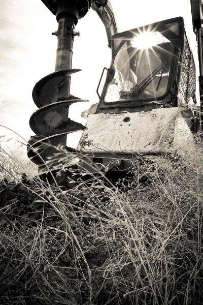A black and white photo of a bulldozer digging a hole in the ground.