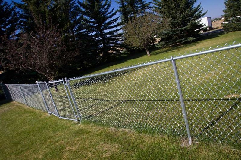 A chain link fence surrounds a lush green field.