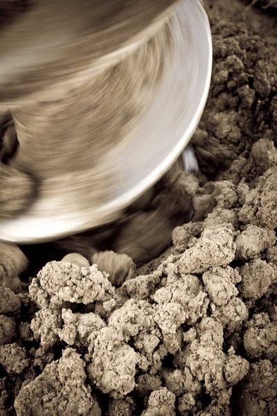 A person is mixing a pile of dirt in a bowl.