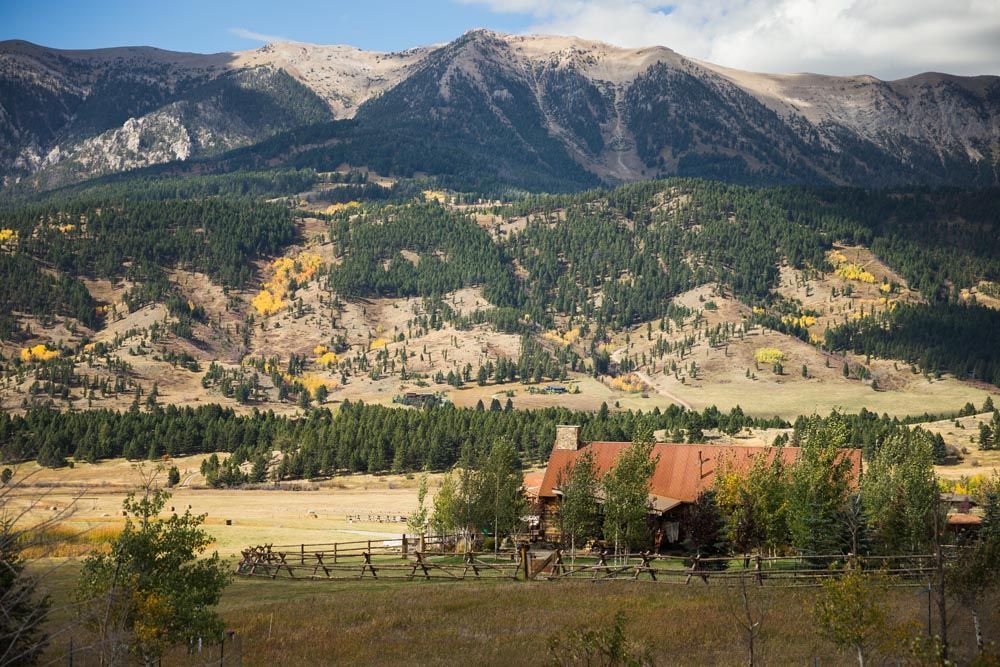 A house in the middle of a field with mountains in the background.