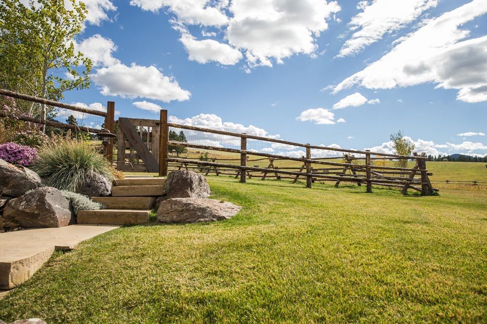 A wooden fence surrounds a grassy field with stairs leading to it.