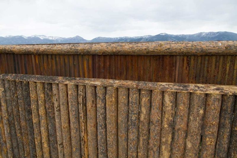 A wooden fence made of logs with mountains in the background.