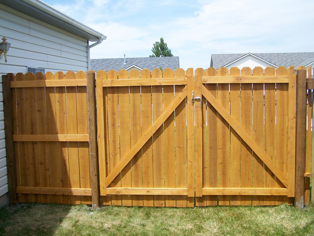 A wooden fence with a gate and a house in the background