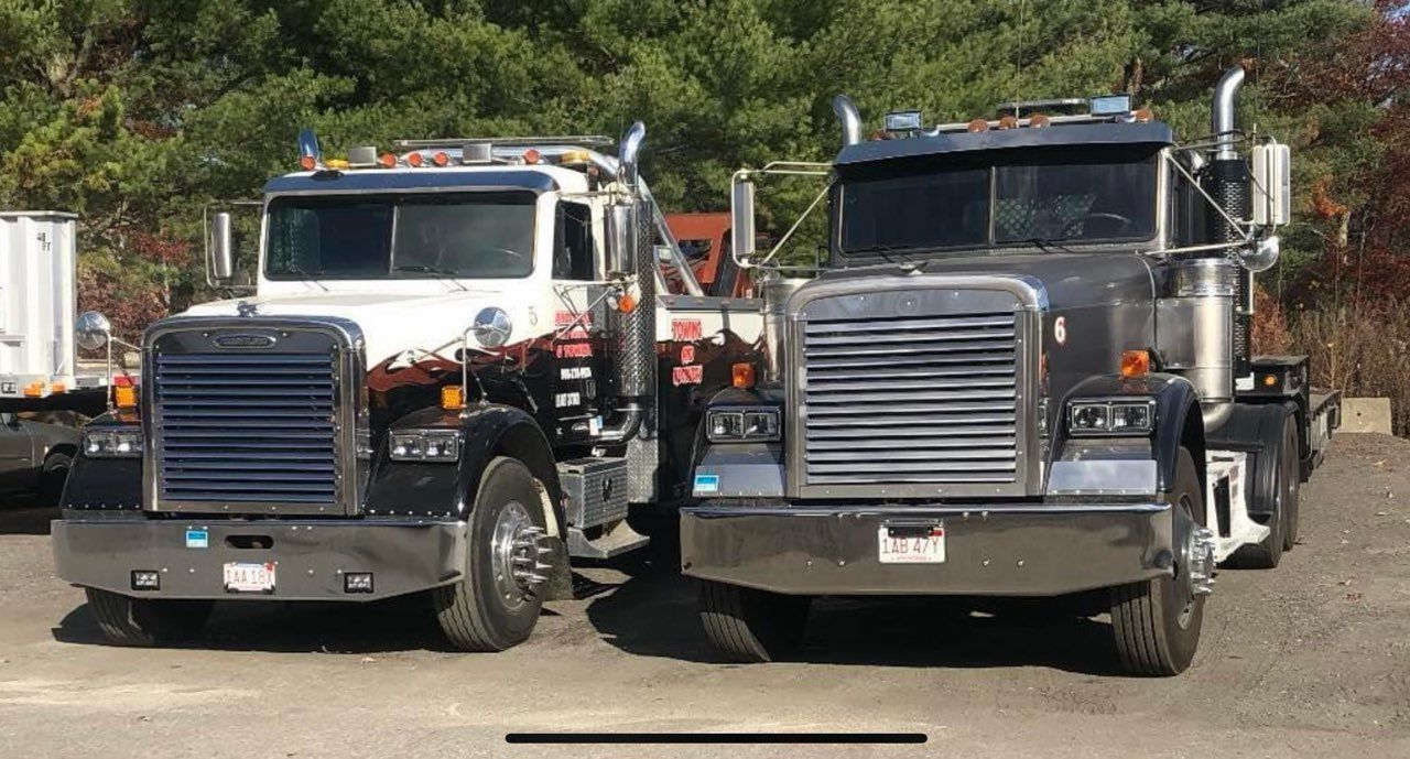 Two large semi-trucks, one white and one black, parked side by side outdoors.