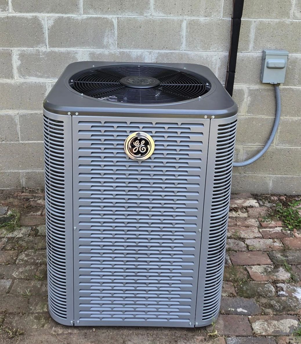 A ge air conditioner is sitting outside of a brick building