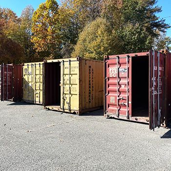 A row of shipping containers are lined up in a parking lot.