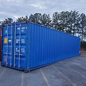 A blue shipping container is parked in a parking lot.