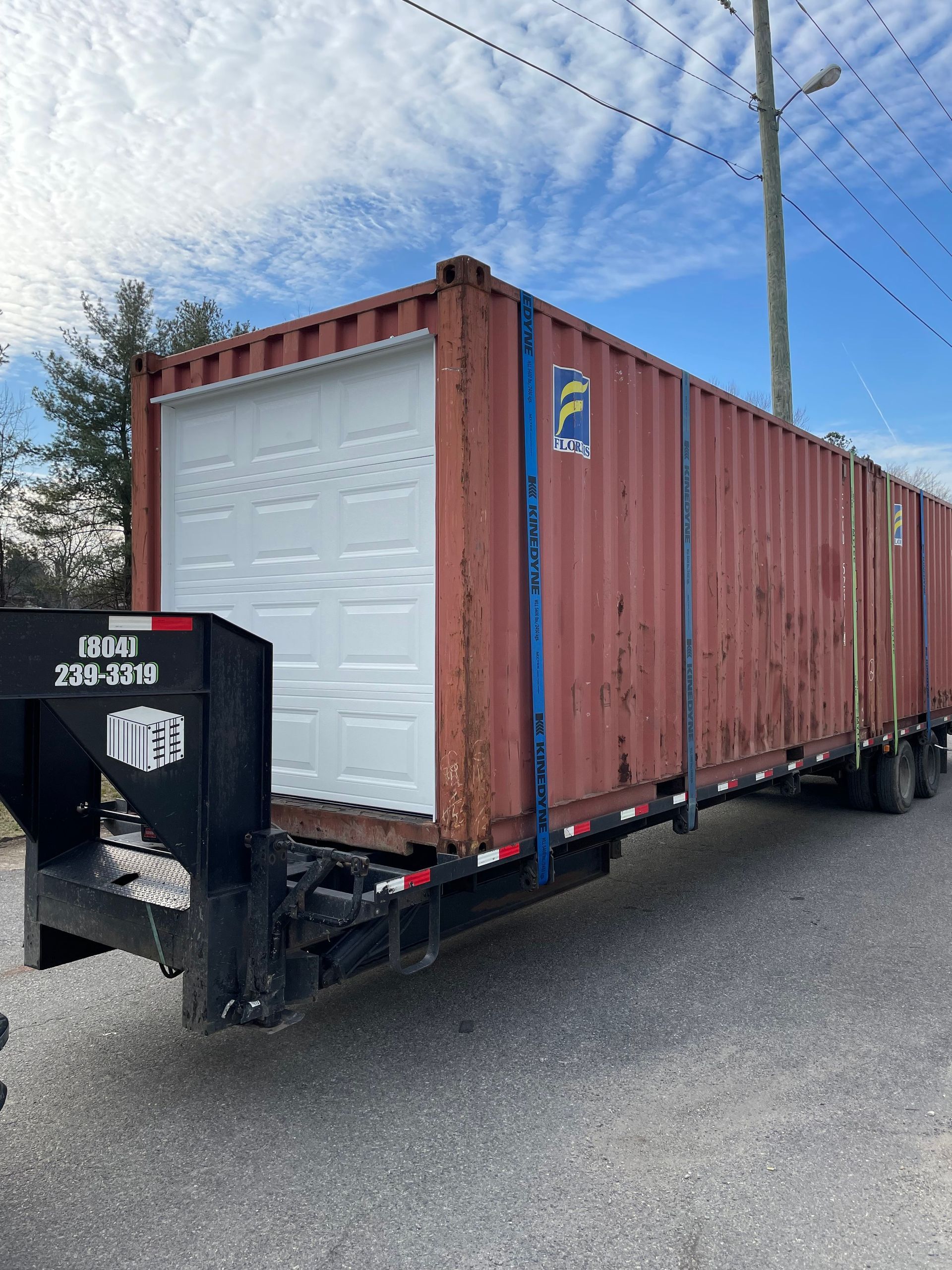 A red shipping container with a garage door attached to it