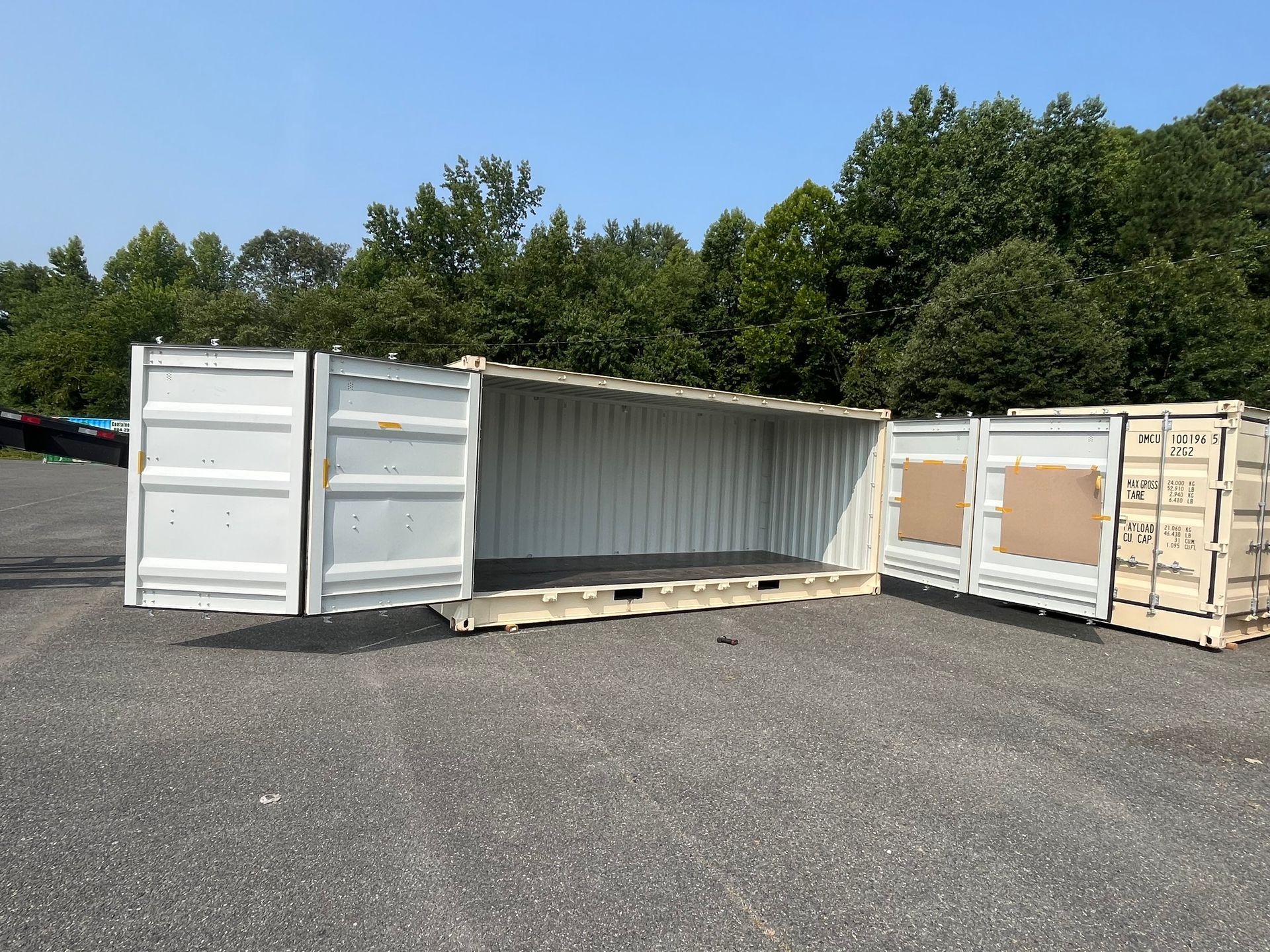 Two shipping containers are sitting in a parking lot with their doors open.