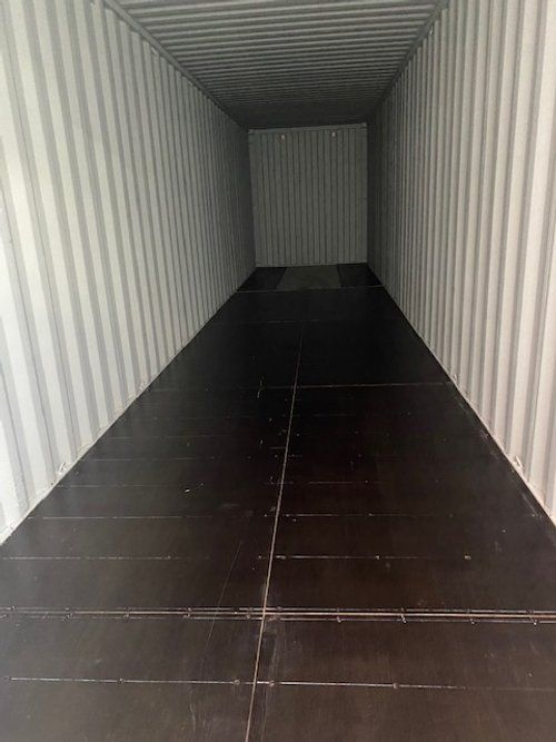 The inside of a shipping container with a black floor.