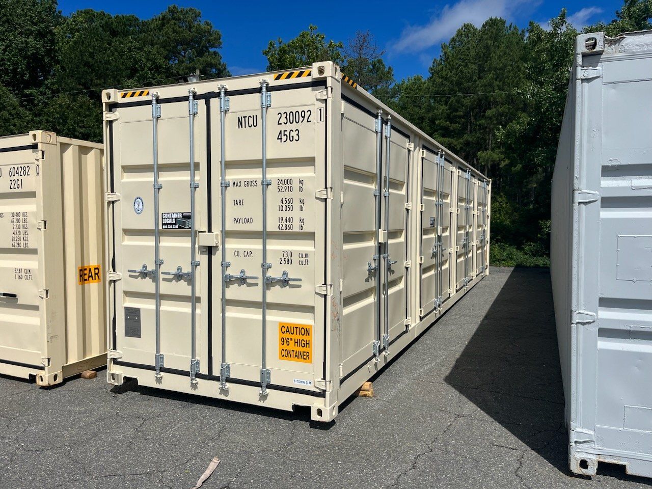 A row of shipping containers are lined up on the side of the road.