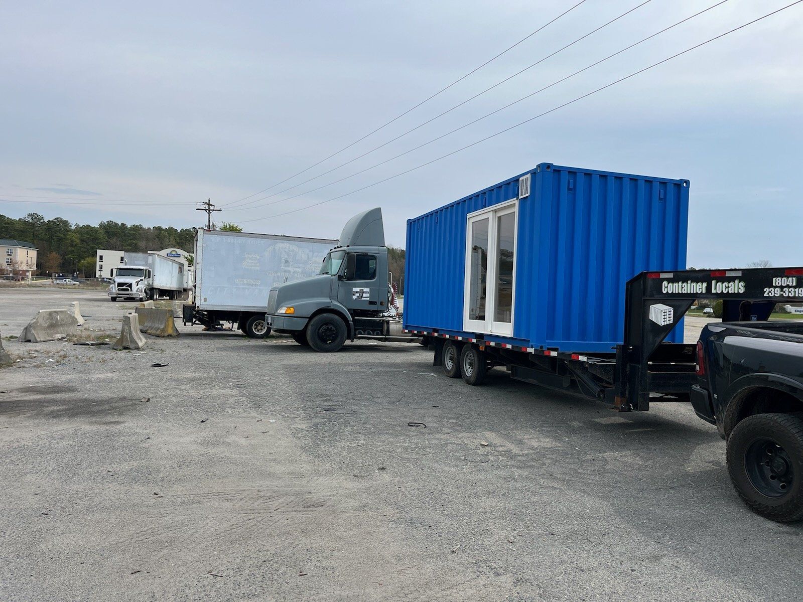 A truck is towing a blue shipping container on a trailer.