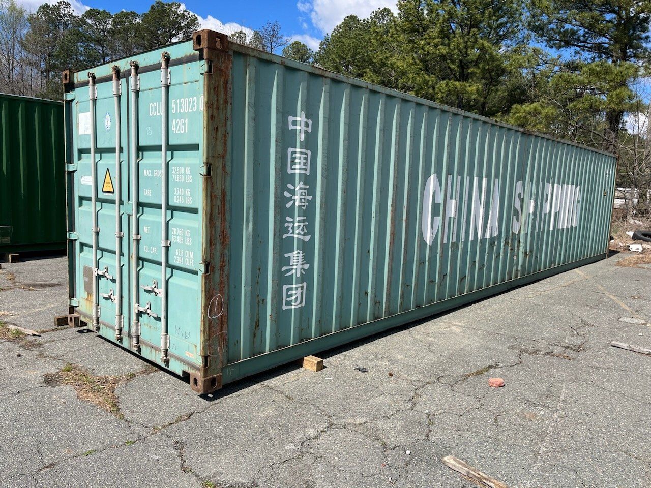 A green shipping container is parked on the side of the road.