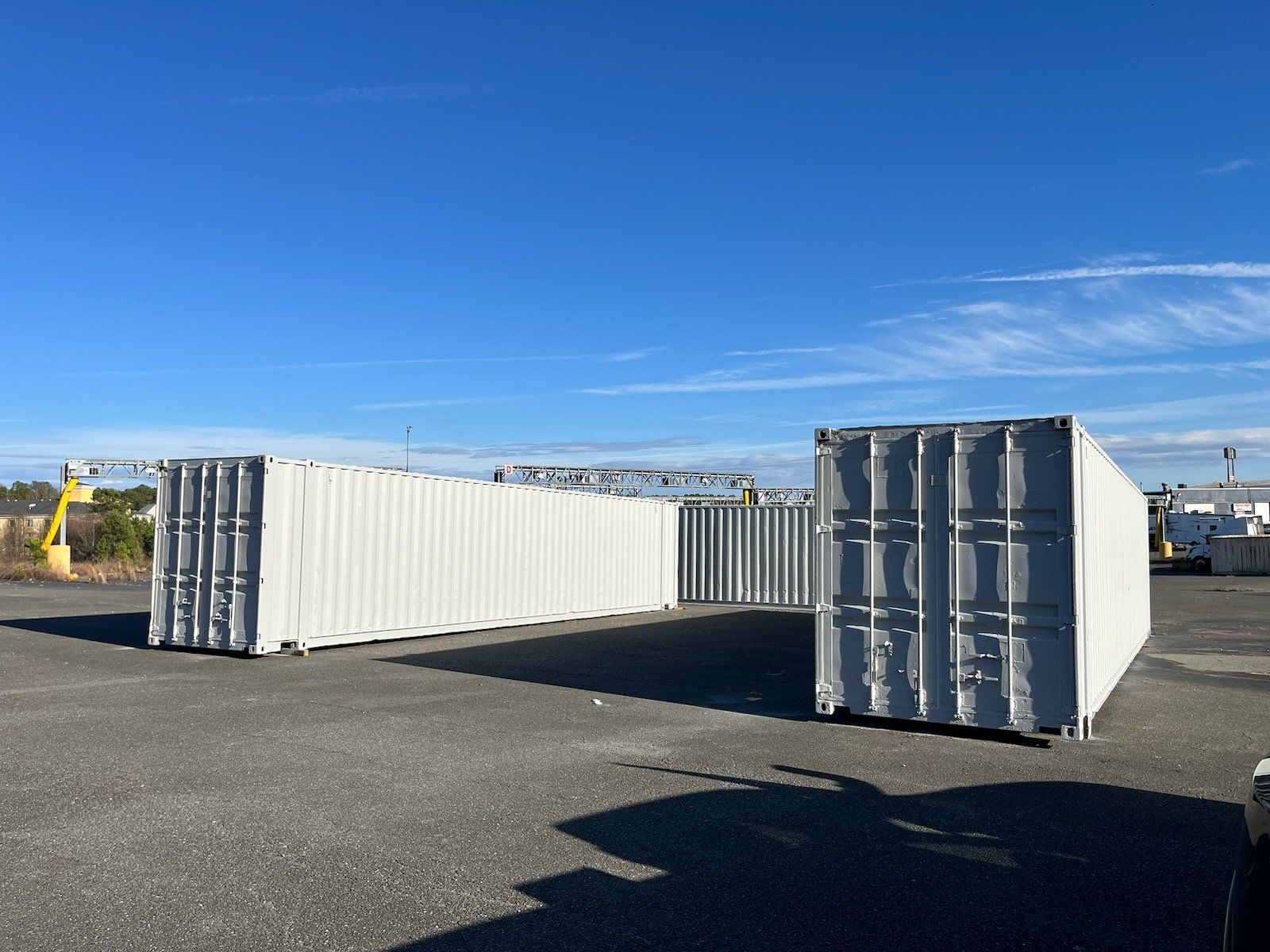 Two white shipping containers are sitting next to each other in a parking lot.