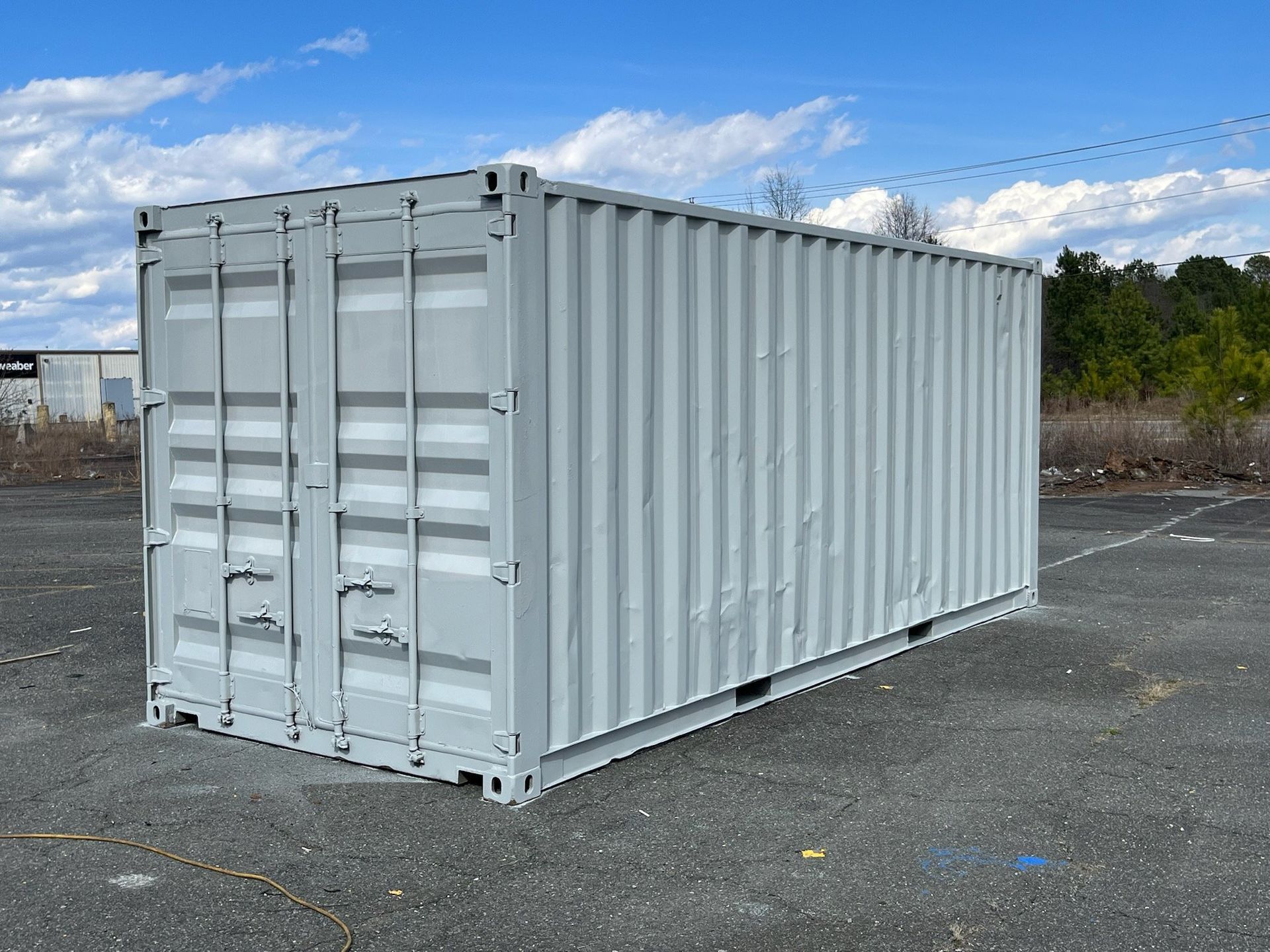 A white shipping container is parked in a parking lot.