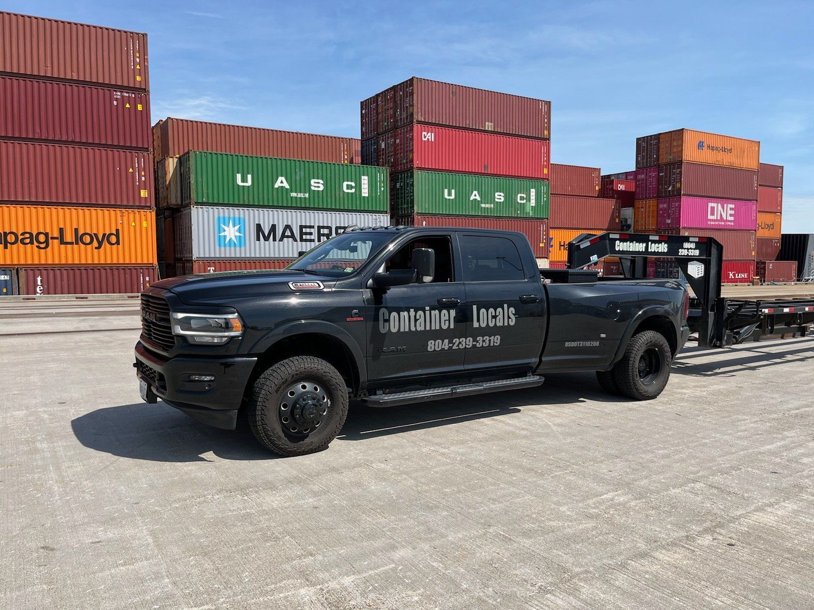 A truck is parked in front of a lot of shipping containers.