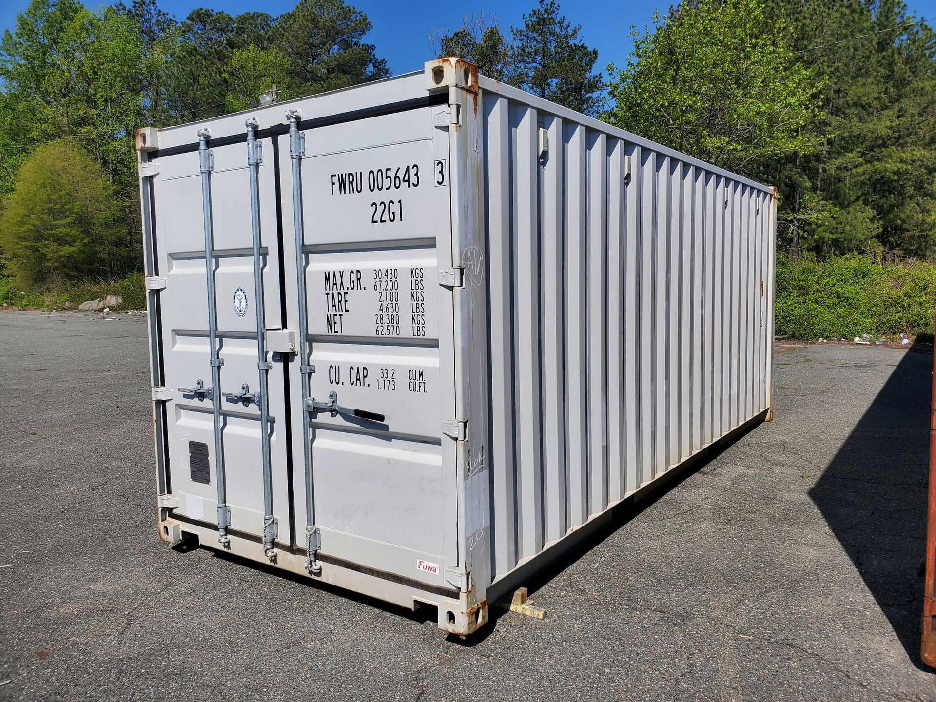 A white shipping container is parked in a parking lot.