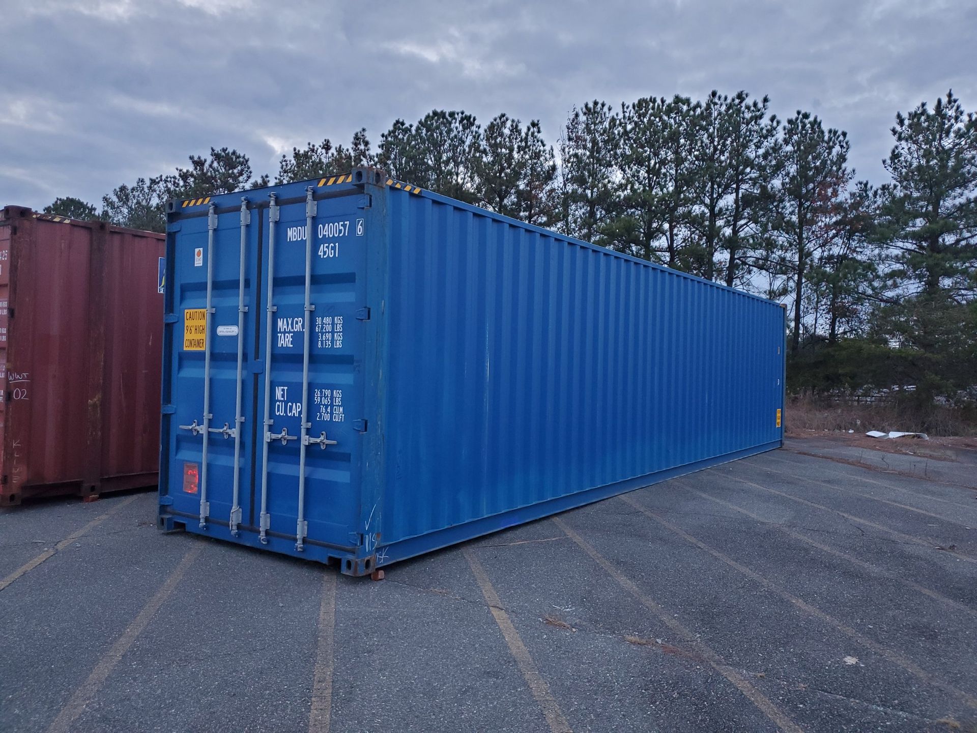 A blue shipping container is sitting in a parking lot
