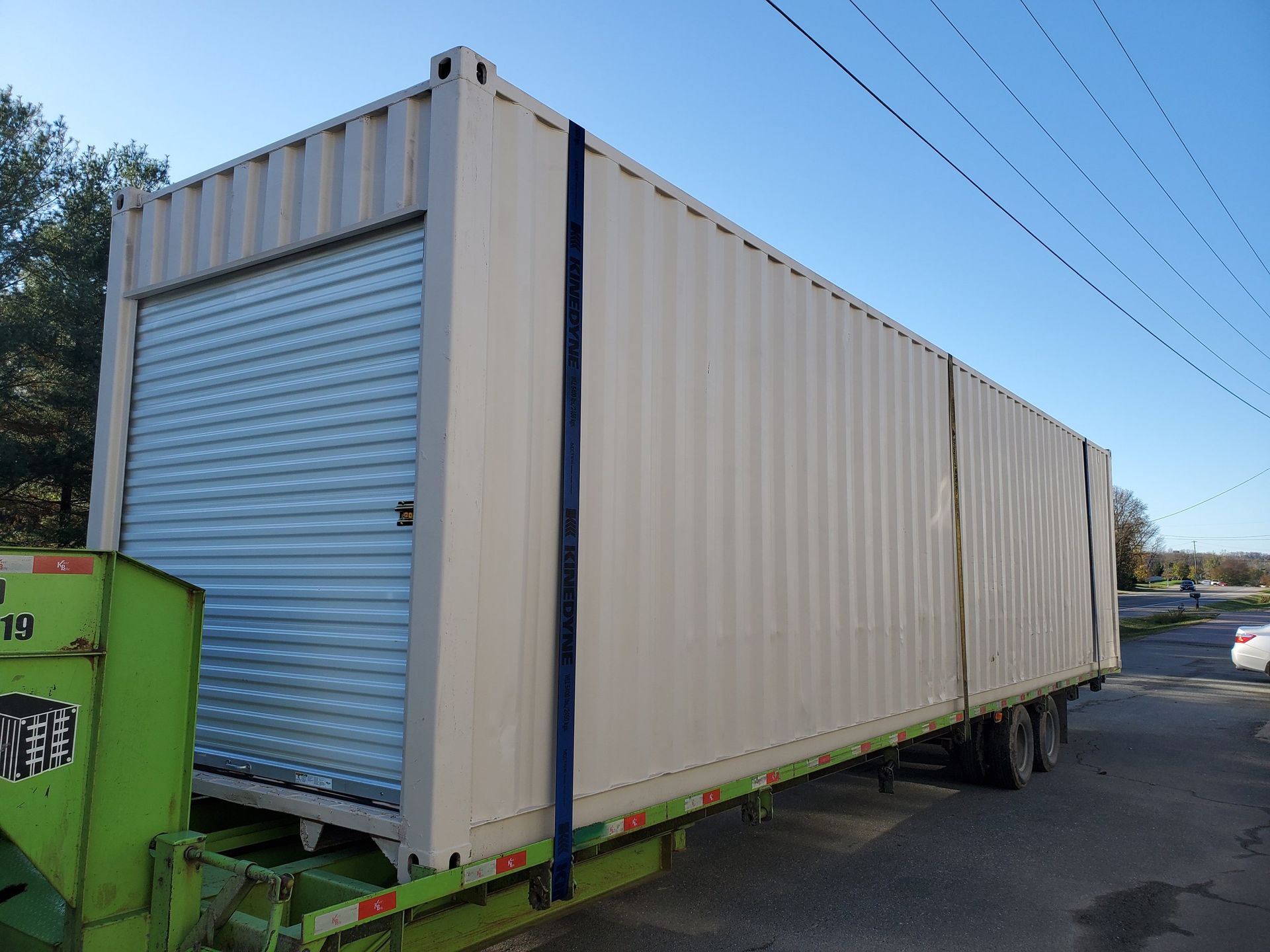A large shipping container is sitting on top of a green trailer.