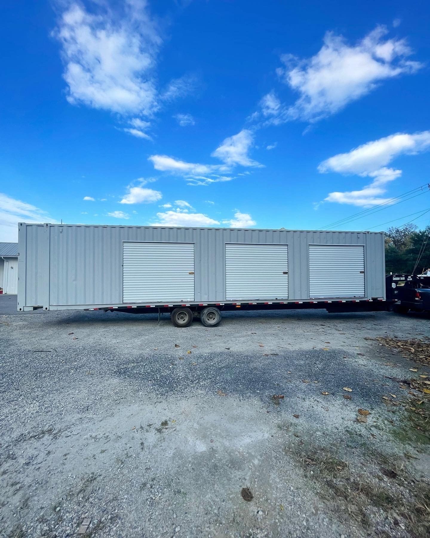 A large white trailer is parked in a gravel lot.