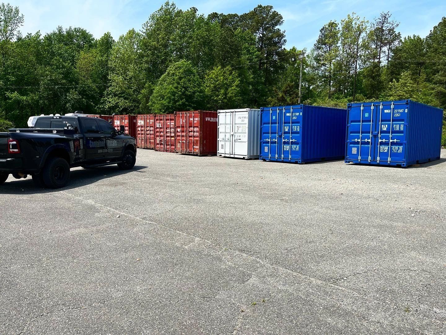 A truck is parked next to a row of shipping containers