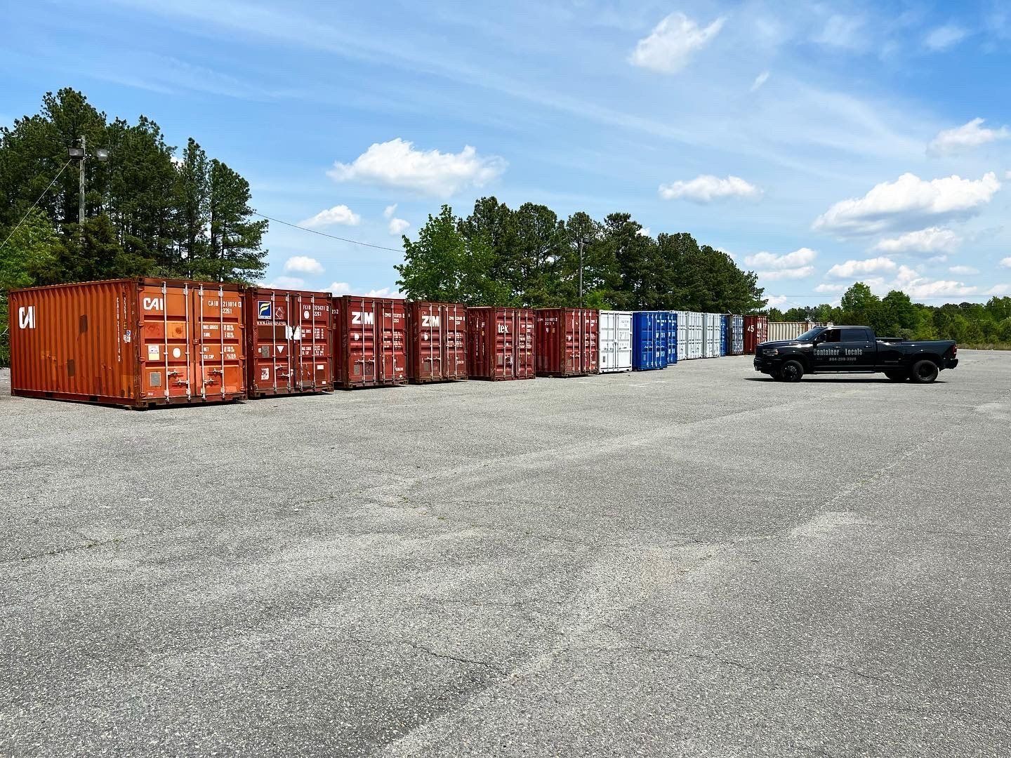 A truck is parked next to a row of shipping containers