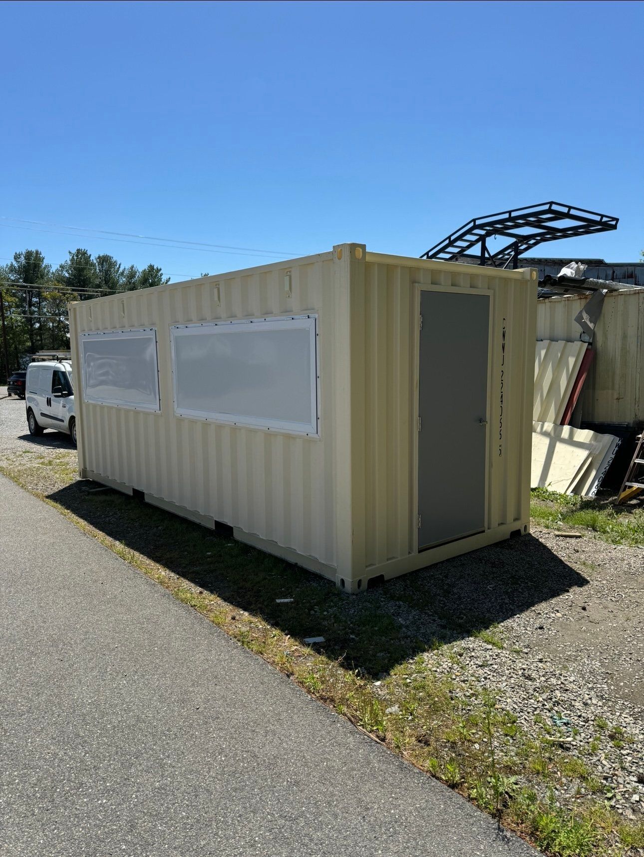 A shipping container is sitting on the side of the road next to a road.
