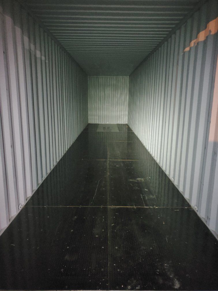 The inside of a shipping container with a black floor.