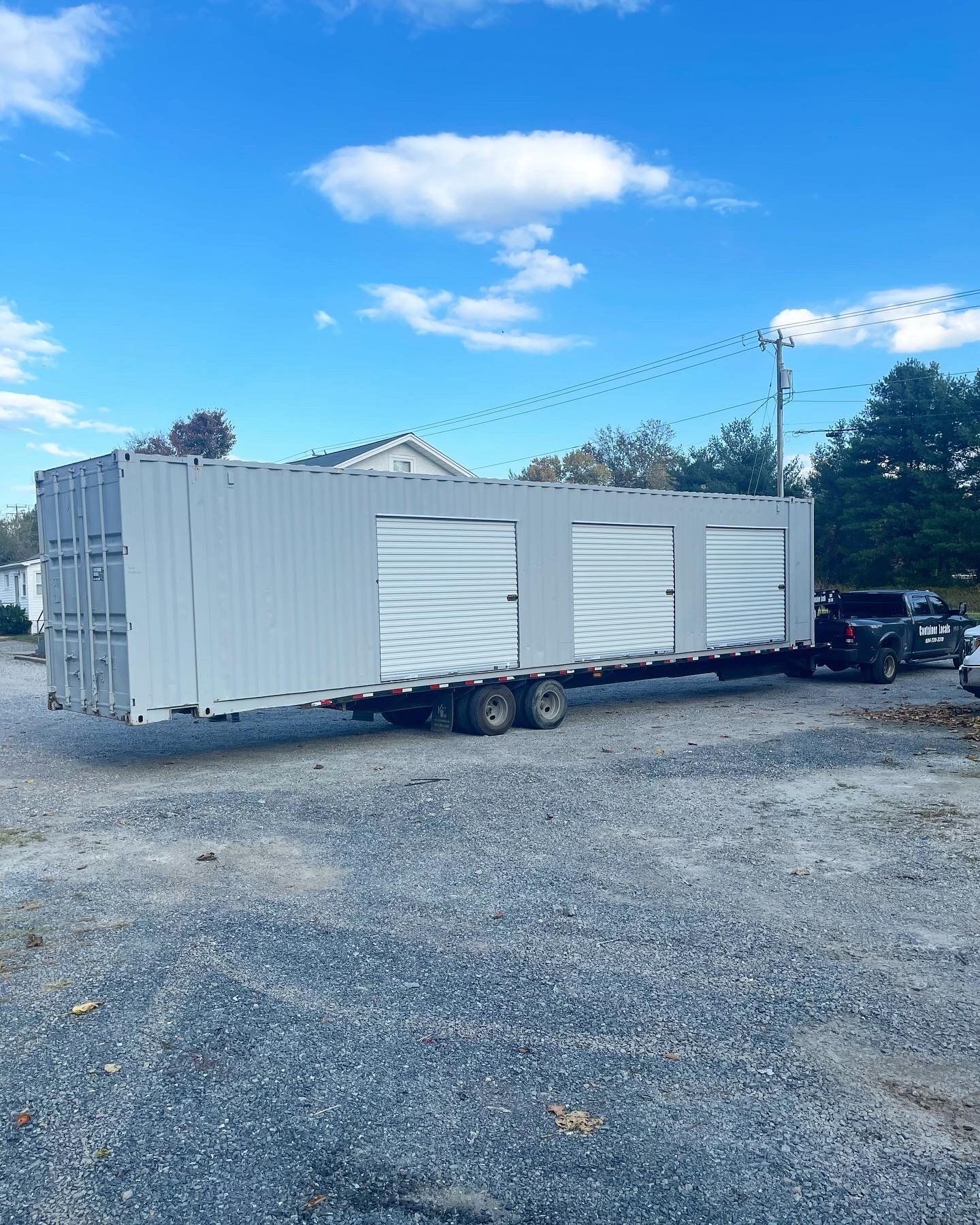 A truck is carrying a large white container on a trailer.